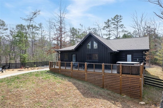 rear view of house featuring board and batten siding, a deck, and fence