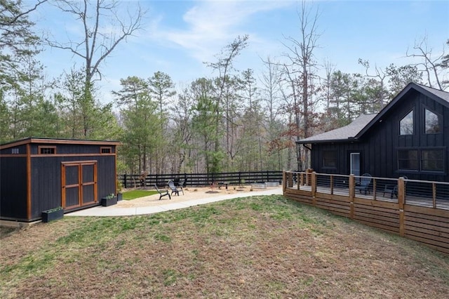 view of yard with an outbuilding, a patio area, a wooden deck, and fence