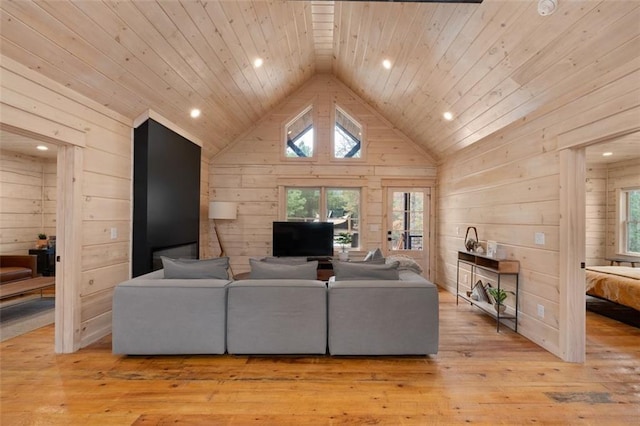 living room featuring light wood finished floors, wooden walls, wooden ceiling, and high vaulted ceiling