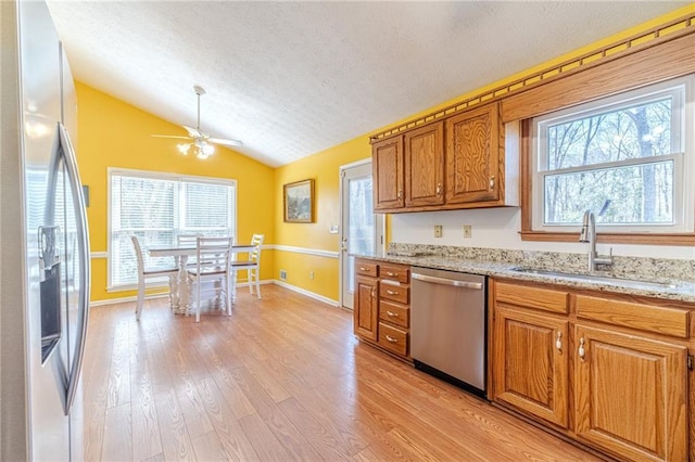 45 Somerset Ct, Covington, GA 30016 - kitchen featuring stainless steel appliances, a ceiling fan, a sink, vaulted ceiling, and brown cabinetry