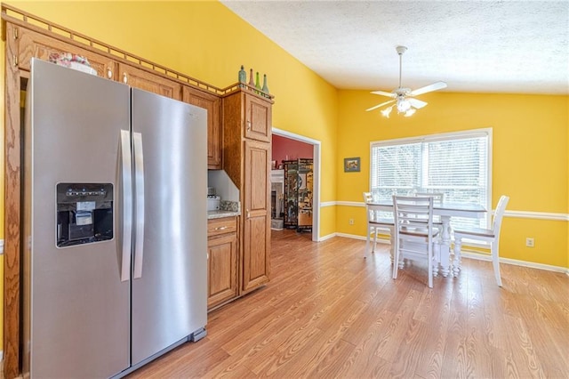 45 Somerset Ct, Covington, GA 30016 - kitchen with lofted ceiling, ceiling fan, brown cabinets, and stainless steel refrigerator with ice dispenser