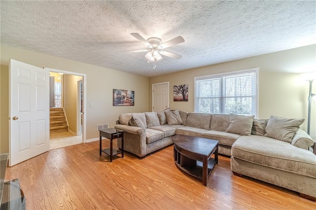 45 Somerset Ct, Covington, GA 30016 - living room featuring a textured ceiling, visible vents, stairs, a ceiling fan, and light wood-style floors