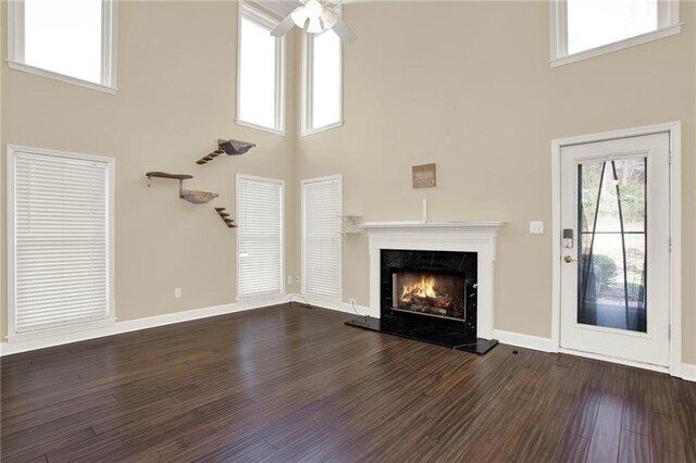 unfurnished living room featuring a fireplace, a high ceiling, and dark hardwood / wood-style floors