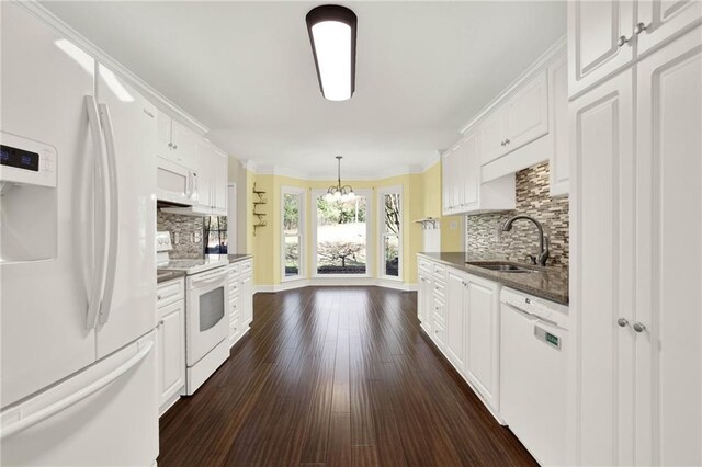 kitchen featuring white appliances, backsplash, sink, hanging light fixtures, and white cabinetry