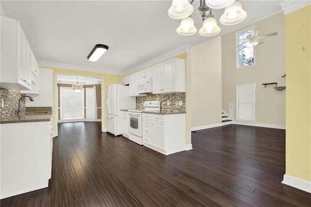 kitchen with tasteful backsplash, white appliances, ceiling fan with notable chandelier, sink, and white cabinets