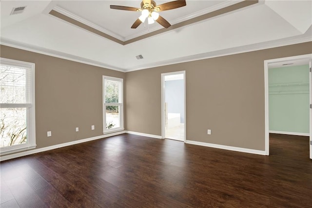 empty room featuring ceiling fan, dark wood-type flooring, crown molding, and a tray ceiling