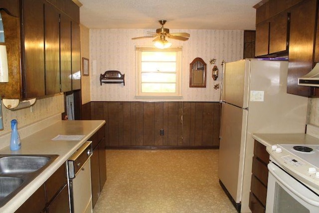 kitchen with ceiling fan, dishwashing machine, wood walls, white electric stove, and dark brown cabinetry