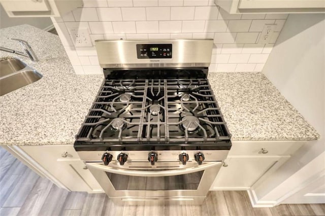 960 Park Place St, Social Circle, GA 30025 - kitchen view of gas range, wood finished floors, decorative backsplash, and light stone countertops