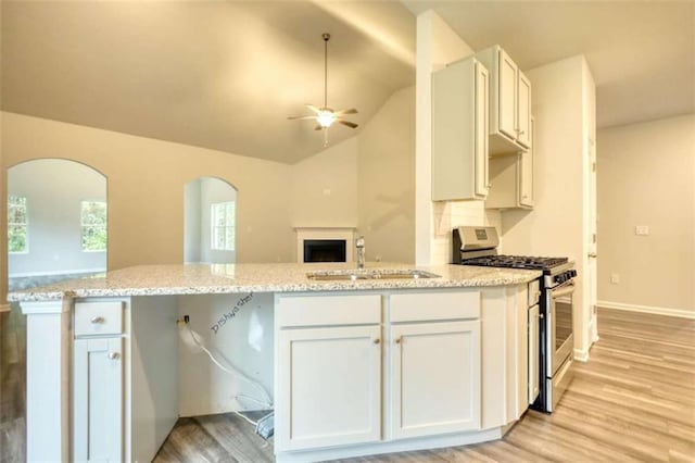960 Park Place St, Social Circle, GA 30025 - kitchen with stainless steel gas range oven, a sink, a ceiling fan, arched walkways, and light wood-style flooring