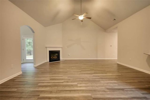 960 Park Place St, Social Circle, GA 30025 - unfurnished living room featuring ceiling fan, a glass covered fireplace, arched walkways, wood finished floors, and high vaulted ceiling