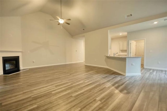 960 Park Place St, Social Circle, GA 30025 - unfurnished living room with a ceiling fan, a glass covered fireplace, wood finished floors, high vaulted ceiling, and baseboards