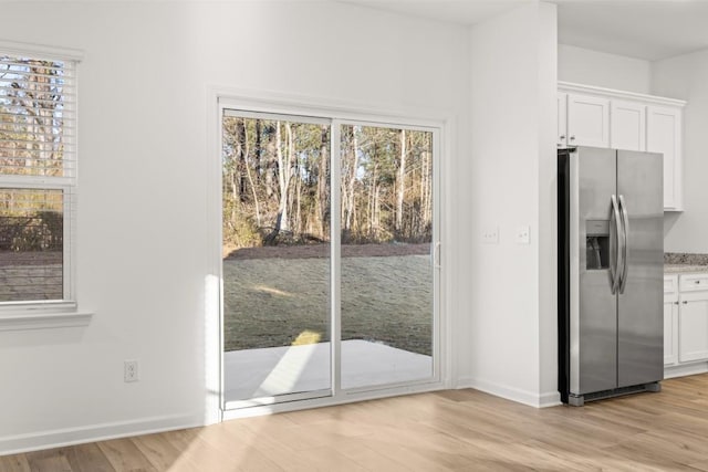 kitchen featuring stainless steel fridge with ice dispenser, white cabinets, and light hardwood / wood-style floors