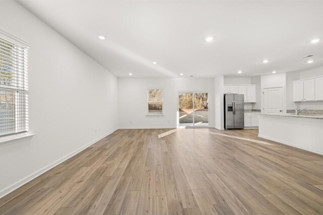 unfurnished living room featuring sink and light wood-type flooring