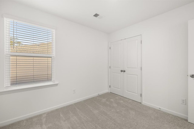 unfurnished bedroom featuring light carpet and a closet