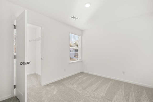 unfurnished bedroom with light carpet, a spacious closet, and a closet