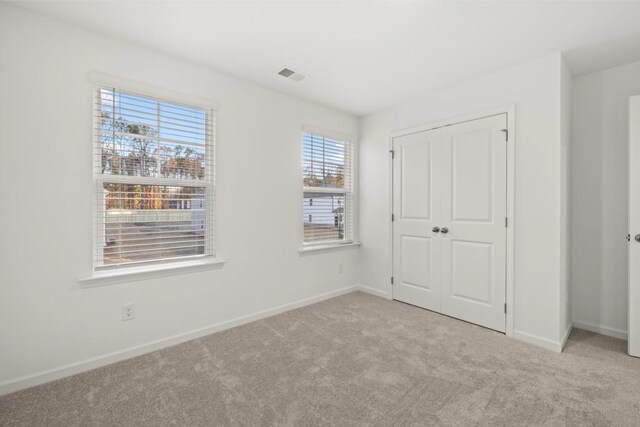 unfurnished bedroom featuring light carpet and a closet