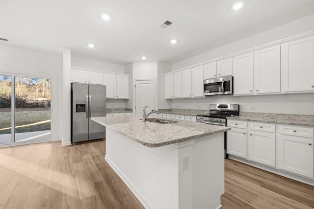 kitchen featuring stainless steel appliances, white cabinetry, a center island with sink, and sink