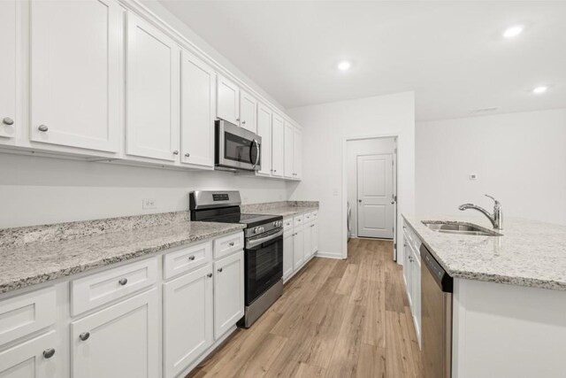 kitchen featuring sink, stainless steel appliances, light stone counters, white cabinets, and light wood-type flooring