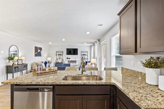 kitchen with kitchen peninsula, sink, light hardwood / wood-style flooring, stainless steel dishwasher, and dark brown cabinetry