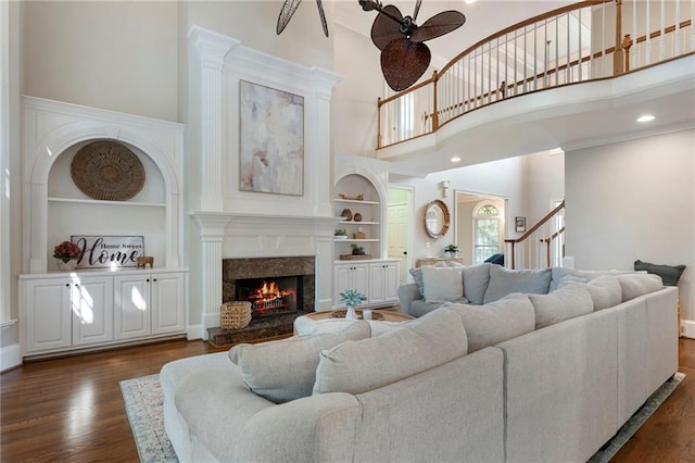 10135 High Falls Pointe Pointe, Johns Creek, GA 30022 - living room featuring a towering ceiling, built in features, dark wood-style flooring, a fireplace, and a ceiling fan