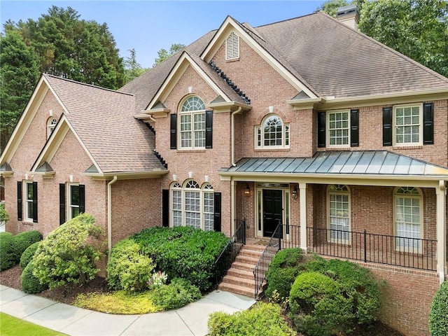 10135 High Falls Pointe Pointe, Johns Creek, GA 30022 - view of front of property with a chimney, brick siding, roof with shingles, covered porch, and a standing seam roof
