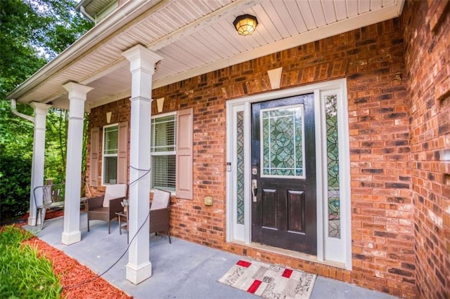 property entrance with a porch and brick siding