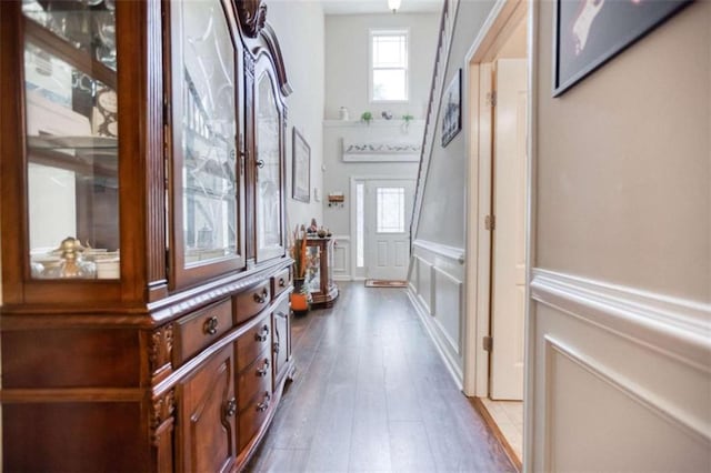 hallway featuring a wainscoted wall, a decorative wall, and wood finished floors