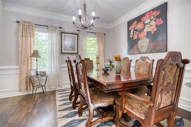 dining room featuring a chandelier, wood finished floors, ornamental molding, a wainscoted wall, and a decorative wall