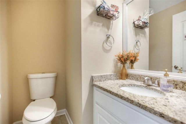 half bath featuring vanity, toilet, tile patterned floors, and baseboards