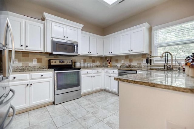 kitchen with appliances with stainless steel finishes, tasteful backsplash, white cabinets, and light stone counters