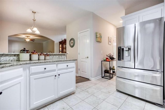 kitchen featuring stainless steel fridge, light tile patterned floors, white cabinets, pendant lighting, and light stone counters