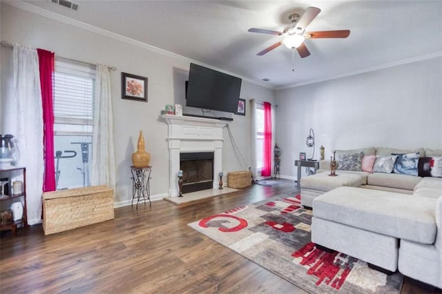 living room with ceiling fan, crown molding, wood finished floors, a fireplace with raised hearth, and baseboards