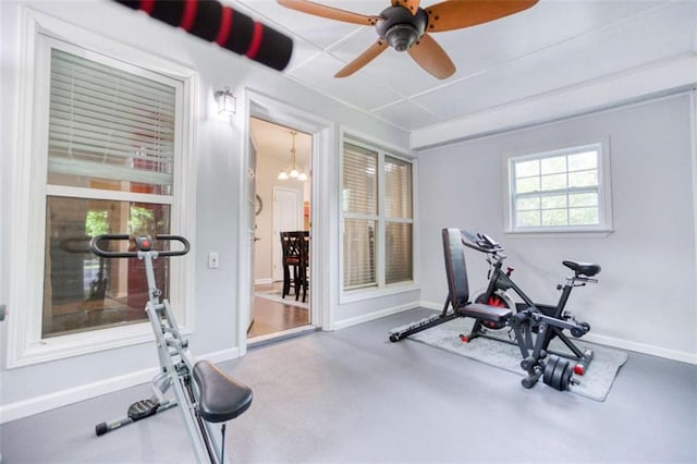 workout room with a ceiling fan, baseboards, and a chandelier