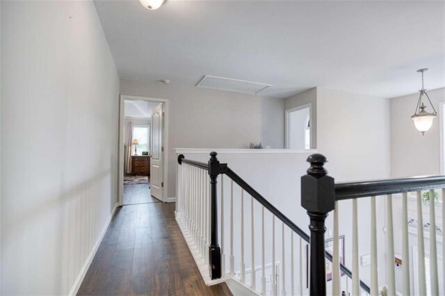 hall with attic access, an upstairs landing, hardwood / wood-style floors, and baseboards