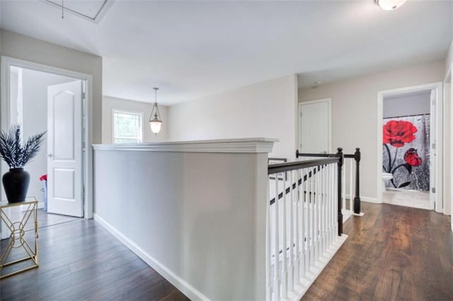 hall with wood finished floors, baseboards, attic access, and an upstairs landing