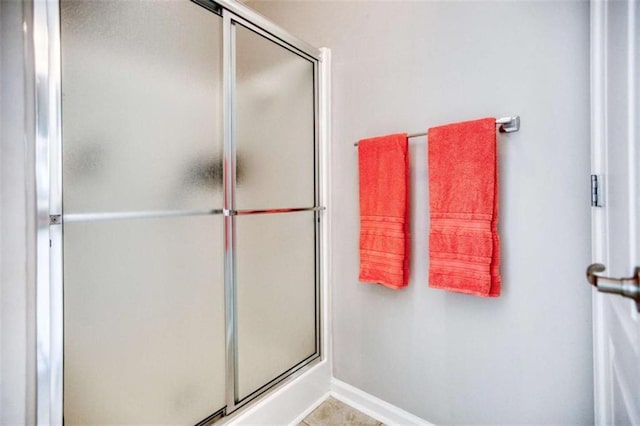 full bath featuring a shower stall and baseboards