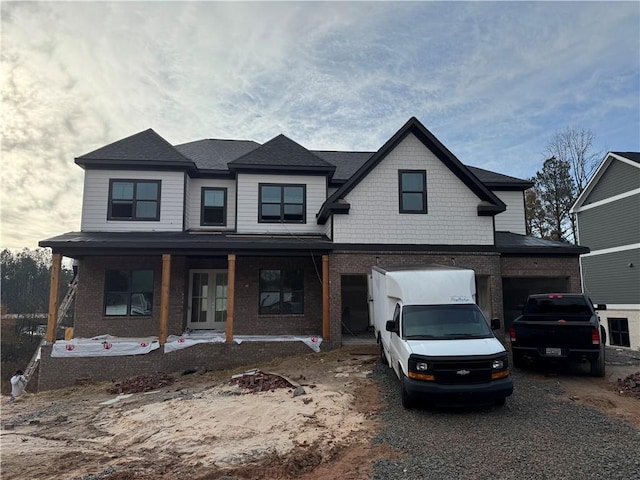 view of front of property with driveway, a shingled roof, and brick siding