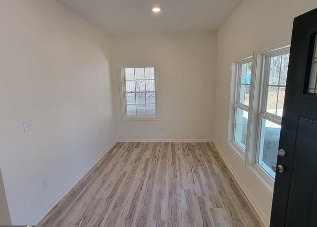 unfurnished room with light wood-type flooring, recessed lighting, plenty of natural light, and baseboards