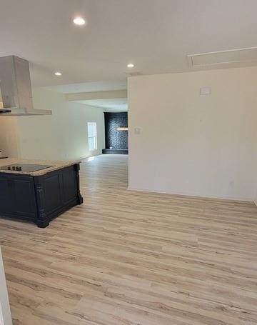 kitchen with open floor plan, dark cabinets, range hood, black electric stovetop, and light countertops