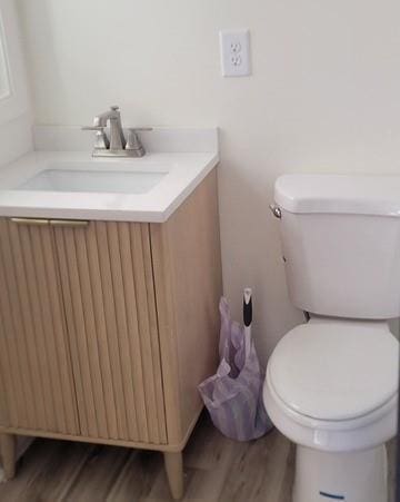 bathroom with toilet, wood finished floors, and vanity