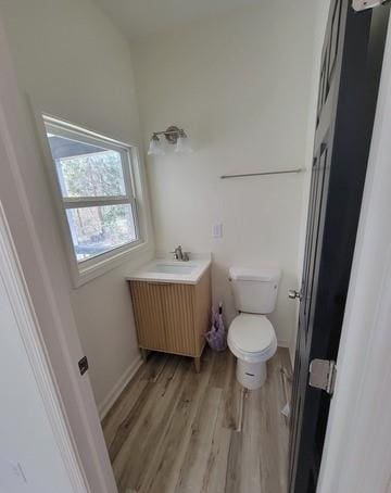 half bath featuring vanity, wood finished floors, toilet, and baseboards