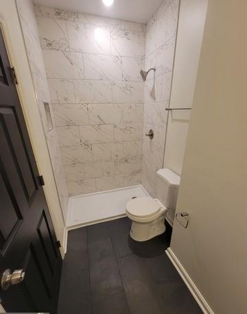 full bath with tile patterned flooring, baseboards, a shower stall, and toilet