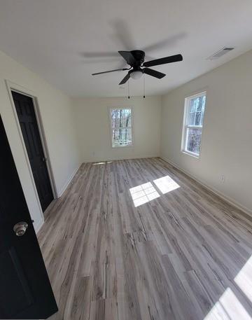 empty room featuring light wood finished floors, a wealth of natural light, and visible vents