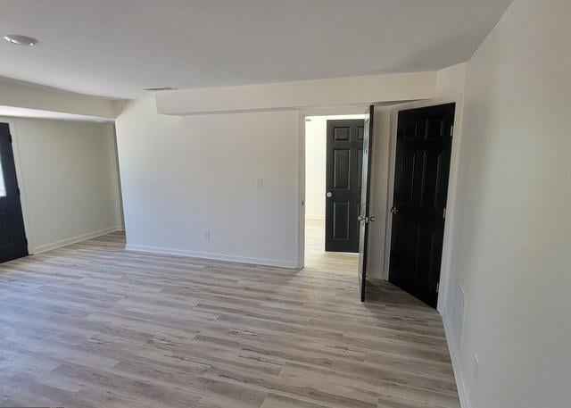 empty room with baseboards, visible vents, and light wood finished floors