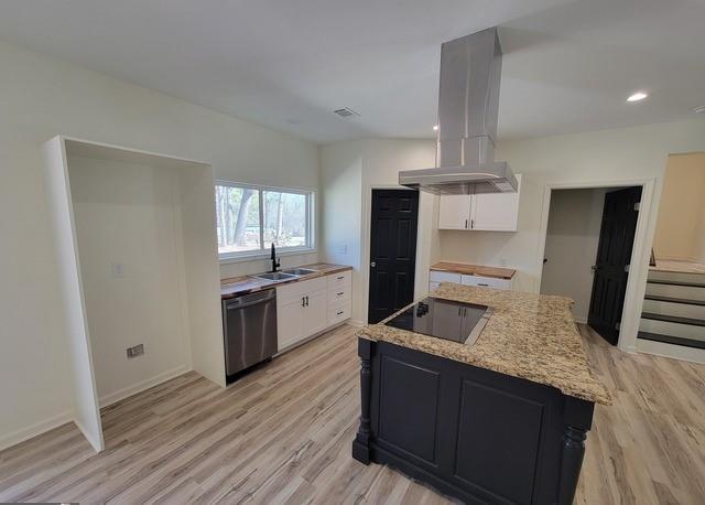 kitchen featuring stainless steel dishwasher, a kitchen island, island exhaust hood, and white cabinets