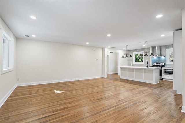 unfurnished living room featuring sink and light hardwood / wood-style flooring