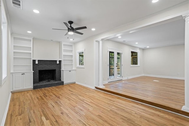 unfurnished living room featuring french doors, built in shelves, ceiling fan, a fireplace, and light hardwood / wood-style floors