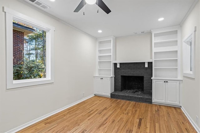 unfurnished living room with ceiling fan, a healthy amount of sunlight, a fireplace, and light hardwood / wood-style flooring