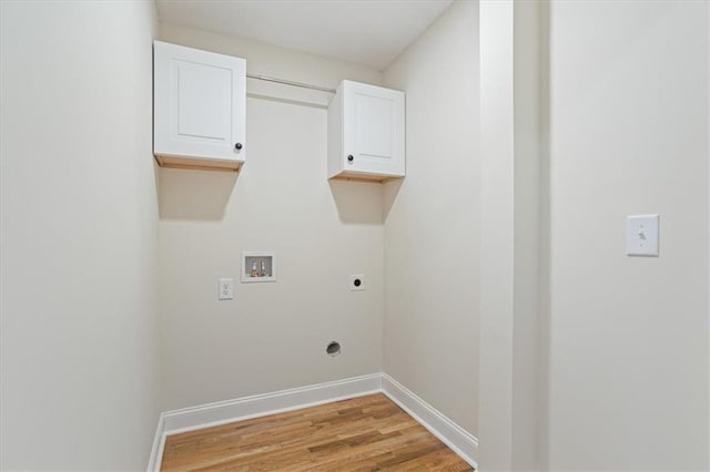 laundry area with hookup for an electric dryer, washer hookup, light wood-type flooring, and cabinets