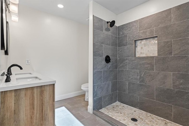 bathroom with tiled shower, vanity, toilet, and tile patterned flooring